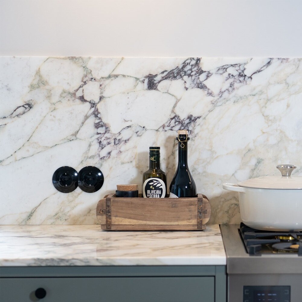 Beispiel einer Installation Berker Serie 1930 Steckdosen rund mit Abdeckplatte in Schwarz auf Wand mit Marmorplatten