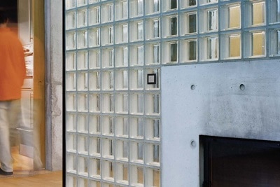 Beispiel einer Installation Berker Enocean Taster mit in Grau und schwarzem Rahmen auf Wand mit Glasbausteinen neben Kamin