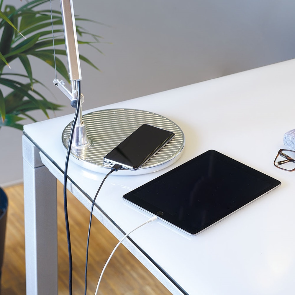 Blick auf Schreibtisch mit u.a. Smartphone und Tablet, die über USB-Kabel geladen werden