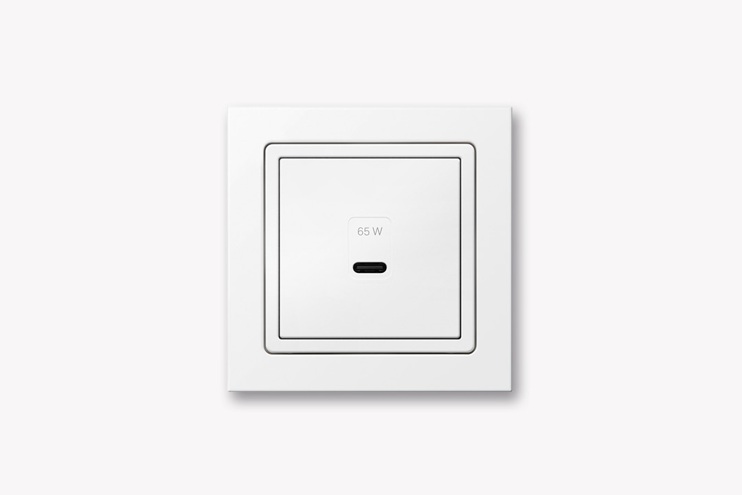 Frontalansicht Berker Q.3 USB-Ladedose 65 Watt mit einer USB-C-Buchse und Rahmen in Weiß auf grünem Hintergrund