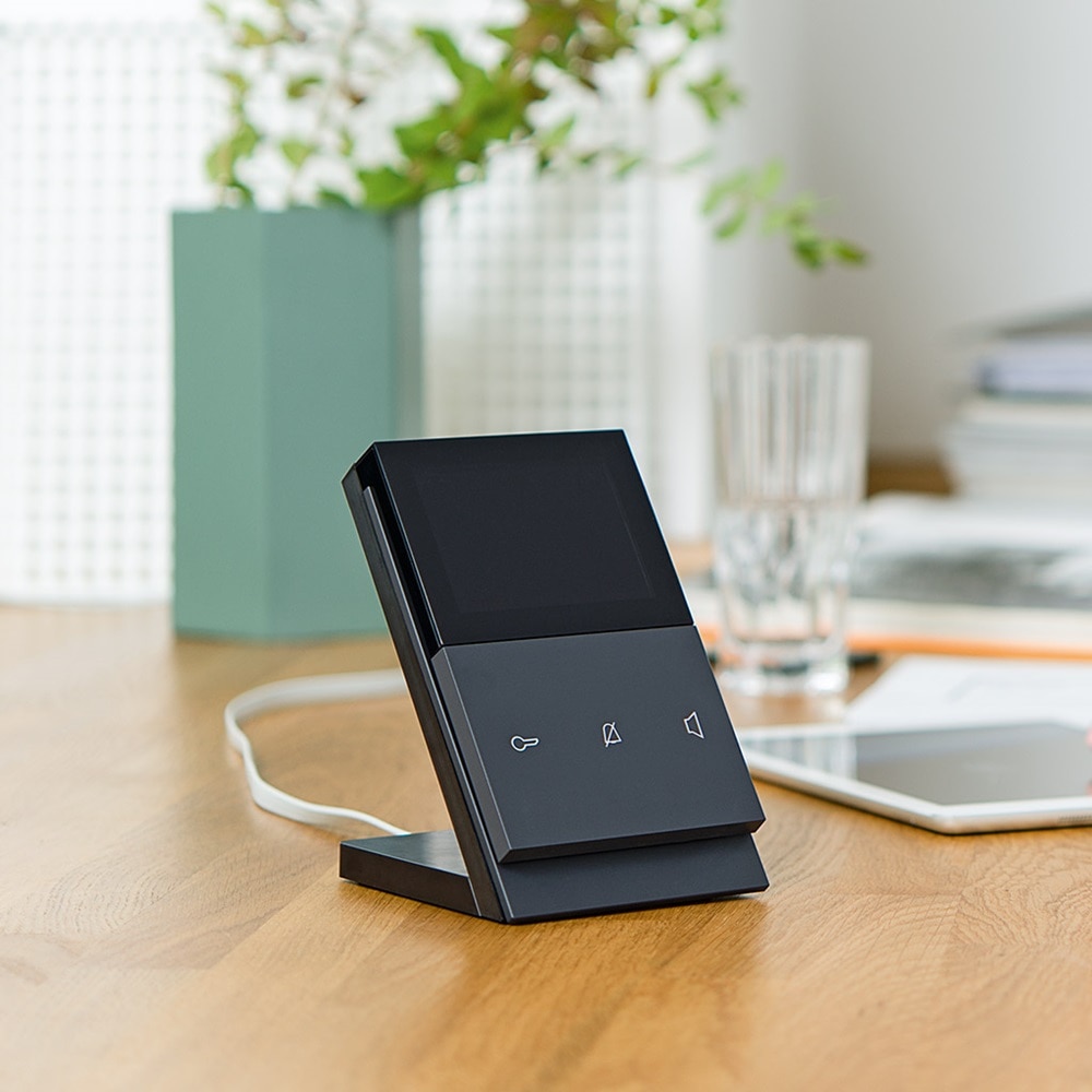 Elcom touch Tischconsole in Schwarz auf Holztisch, woran mit Tablet arbeitende Dame sitzt