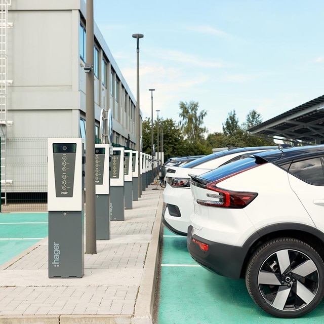 Hager-Elektroauto-Ladestationen auf einem Parkplatz mit zum Laden eingesteckten Fahrzeugen