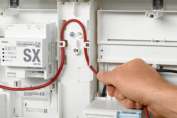 Elektriker verlegt elektrische Leitung unter Nutzung des Hager Kabelmanagement-Systems für 3-Punkt-Zählerplätze