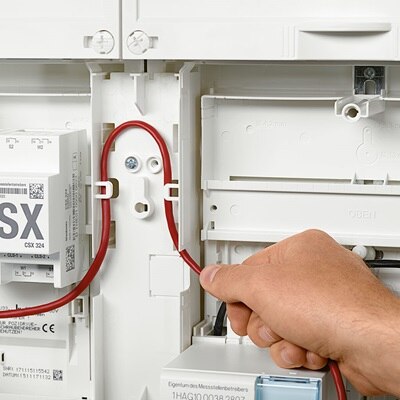 Elektriker verlegt elektrische Leitung unter Nutzung des Hager Kabelmanagement-Systems für 3-Punkt-Zählerplätze