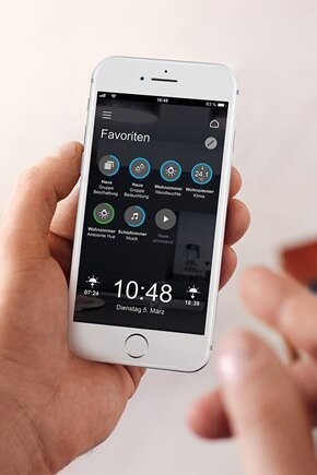 Smartphone in Hand eines Mannes mit Domovea App und Ansicht des Bereichs Favoriten