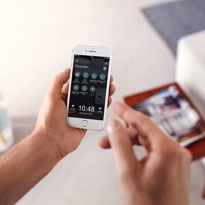 Smartphone in Hand eines Mannes mit Domovea App und Ansicht des Bereichs Favoriten