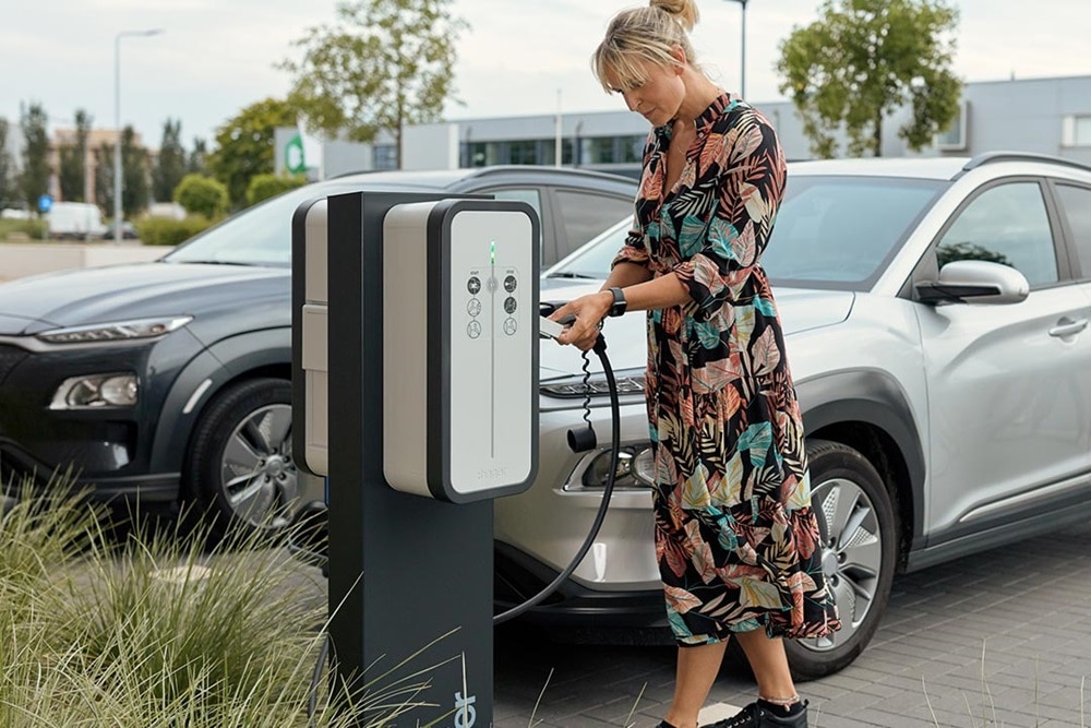 Frau, die Ladeskabel für das Elektroauto an die Hager Witty Share Ladesäule anschließt