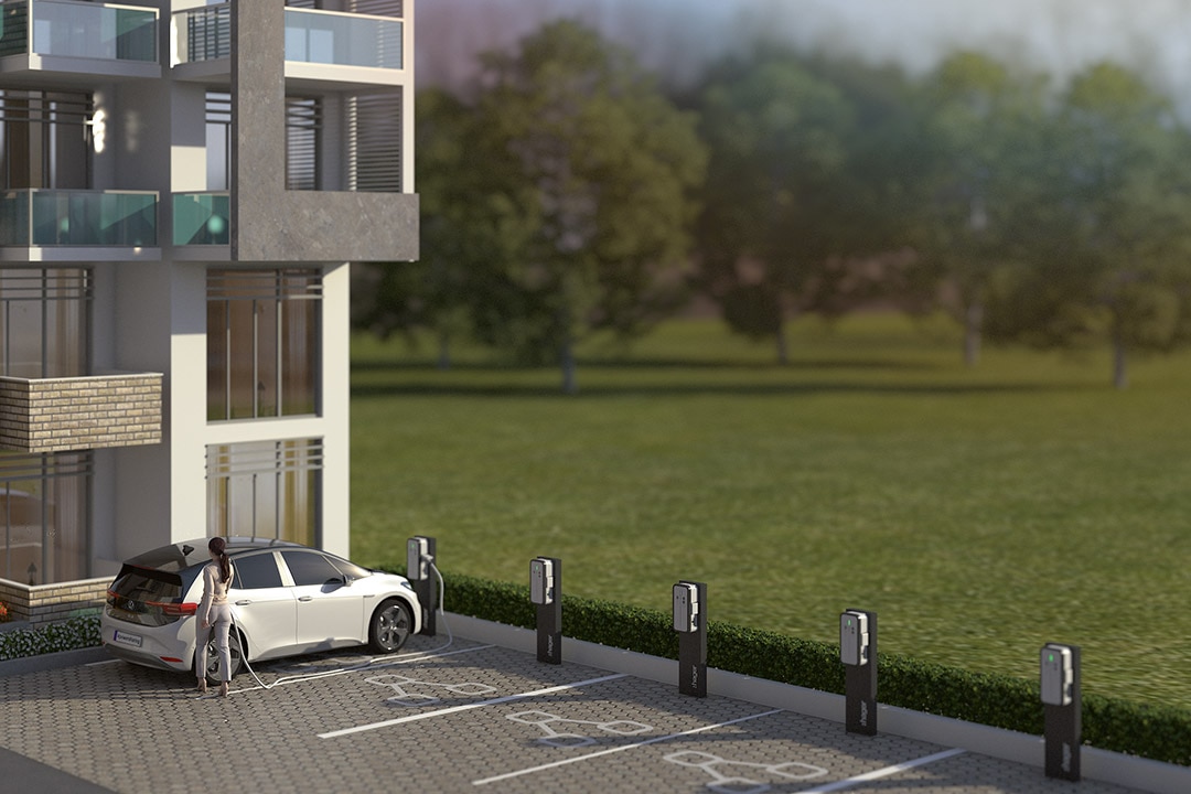 Mehrfamilienhaus mit Parkplatz mit mehreren Hager Witty Ladesäulen und Frau, die ihr Auto laden lässt