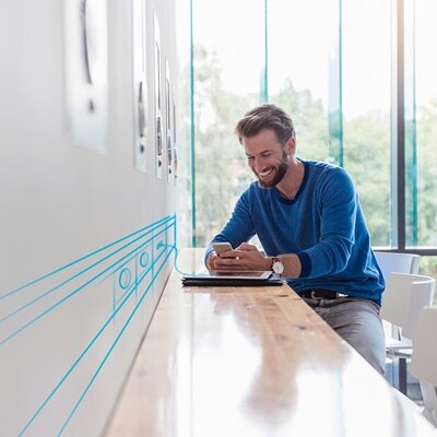 Blick auf Hochtisch mit Mann, der auf Smartphone schaut und Illustration der Energievorsorgung via Brüstungskanal