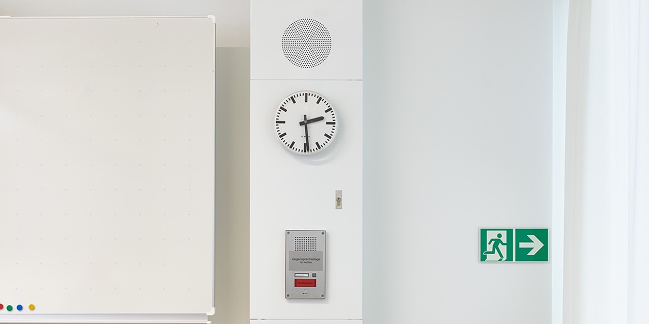 Blick in Klassenraum speziell auf Hager Mediensäule, bestückt u.a. mit Notausschalter, Gegensprechanlage und Uhr