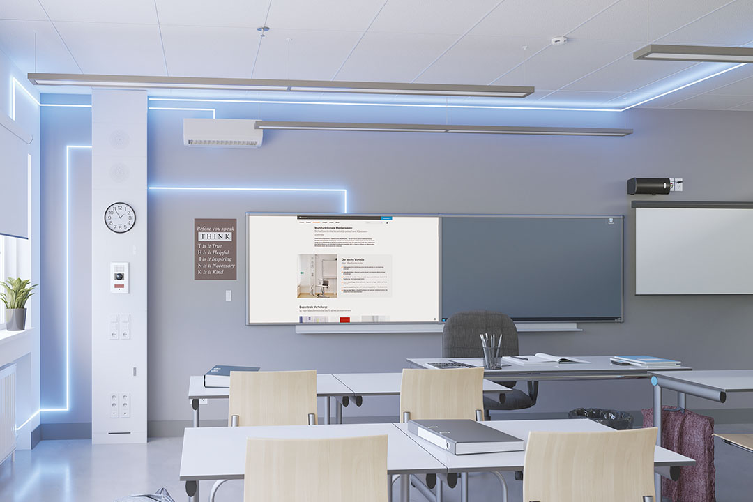 Blick in Klassenzimmer mit Hager Mediensäule links, Whiteboard mit aktivem Projektor in der Mitte sowie Tischen und Bestuhlung davor