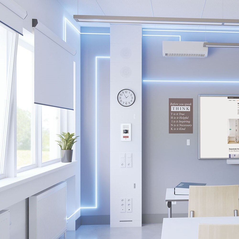 Blick in Klassenzimmer mit Hager Mediensäule links, Whiteboard mit aktivem Projektor in der Mitte sowie Tischen und Bestuhlung davor