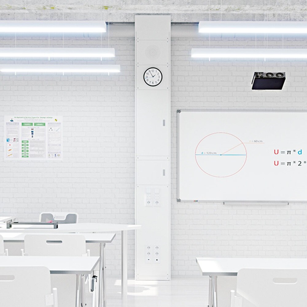 Blick in Klassenzimmer mit weißer Zieglsteinwand woran Hager Mediensäule und Whiteboard montiert sind, davor Tische und Bestuhlung 