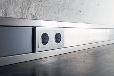 Hager Leitungsführungsschienen am Boden aus Stahlblech mit Berker Steckdosen.