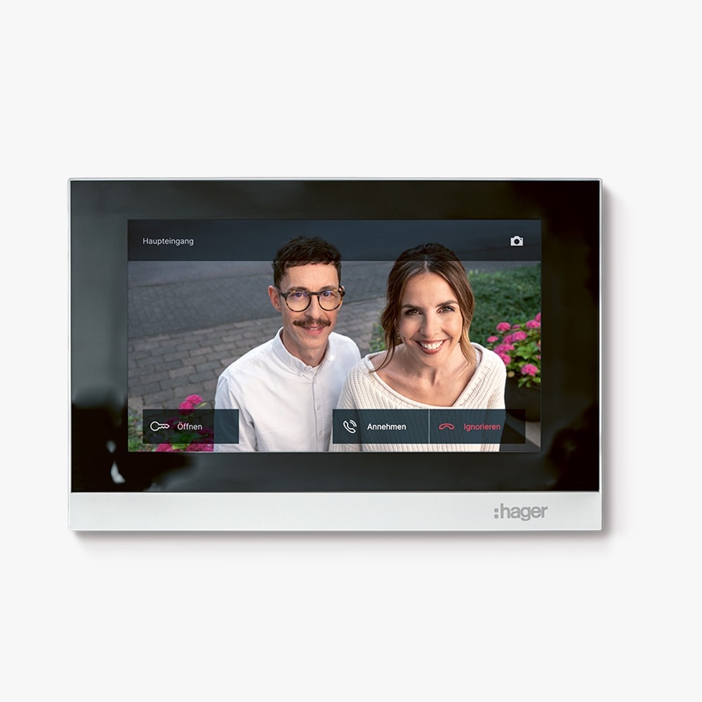 Weiße Video Innenstation Hager intercom view mit Touch-Display worauf ein Mann und eine Frau zu sehen sind, die vor der Haustür an der Außenstation stehen