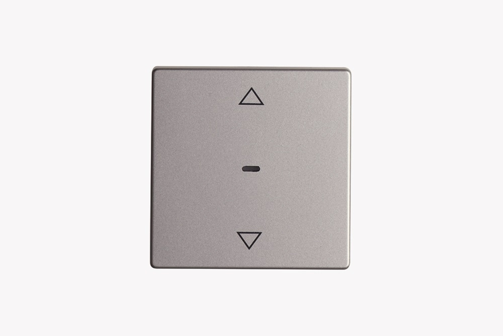 Aluminiumfarbener Jalousie-Taster für KNX-Funksysteme, mit Kontrollleuchte sowie zwei aufgedruckten Pfeilen zur Richtungsangabe für Hoch und Runter