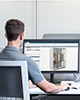 Mitarbeiter arbeitet an elektrischer CAD-Software auf einer Doppelmonitor-Konfiguration in einer Büroumgebung
