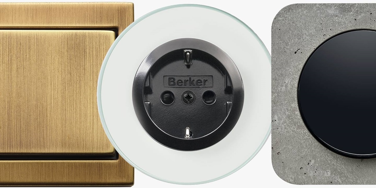 Verschiedene Hager-Elektroschalter und Steckdosendesigns, darunter ein Messing-Kippschalter, eine schwarze Berker-Markensteckdose und ein moderner schwarzer Schalter auf einem Betonhintergrund