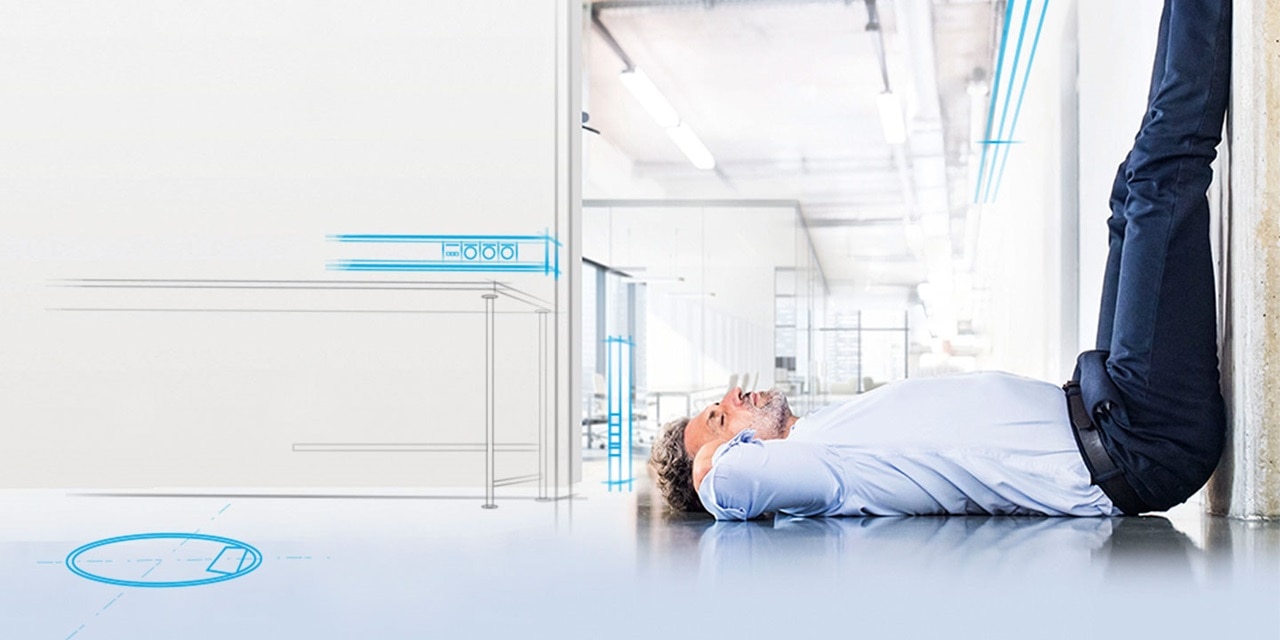 Person liegt auf dem Rücken in einer modernen Büroumgebung mit konzeptionellen blauen Linien, die die Elektroplanung andeuten