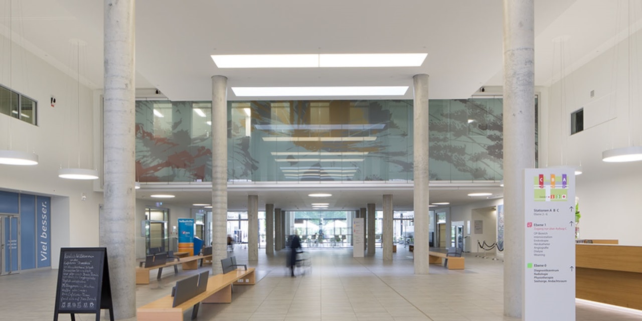 Moderne Bürogebäude-Lobby mit Säulen, Sitzbereich und abgehängten Deckenleuchten