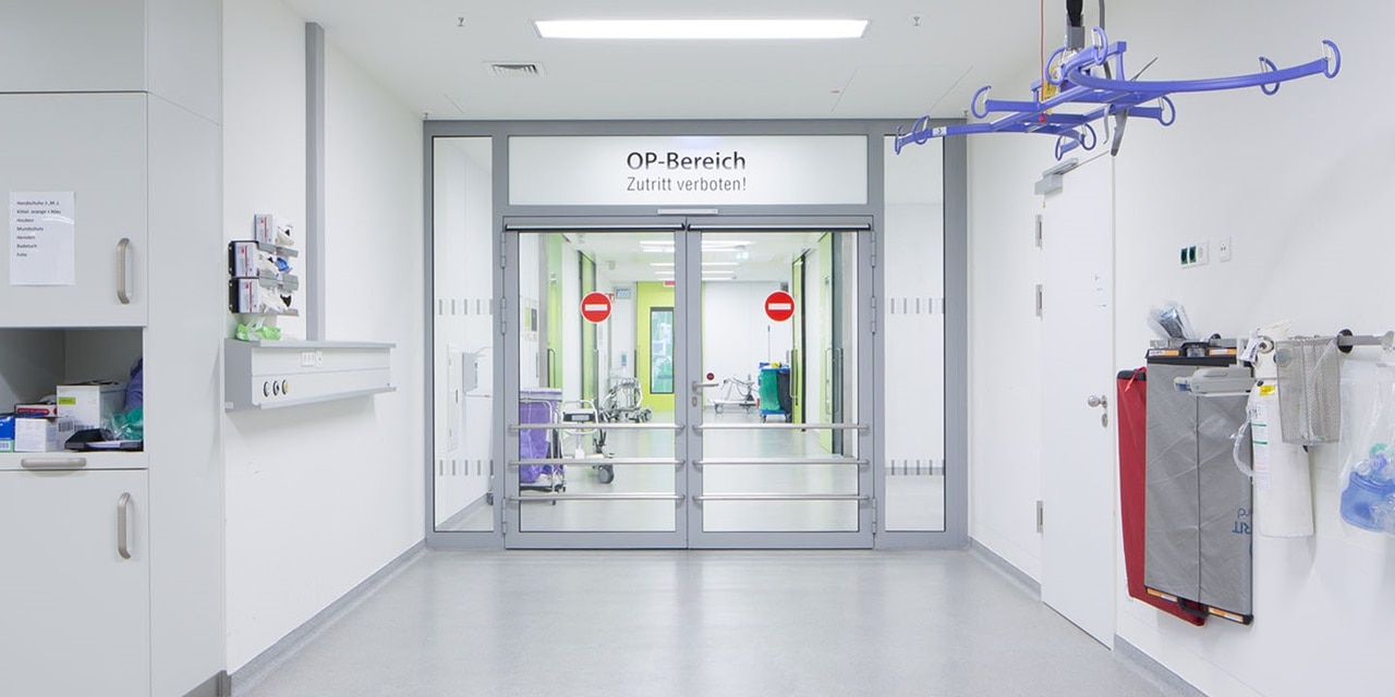 Krankenhausflur mit 'OP-Bereich'-Schild am Eingang, welches einen eingeschränkten Chirurgiebereich anzeigt, mit medizinischer Ausrüstung und sauberer Umgebung