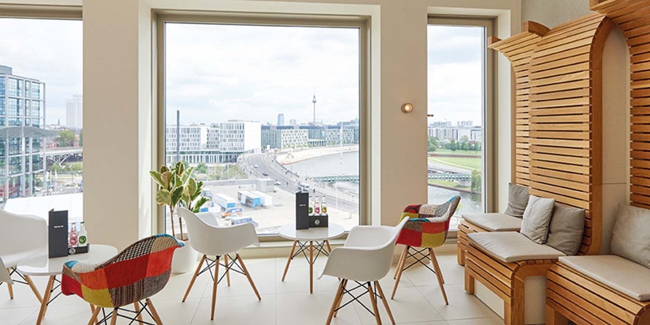 Modernes Wohnzimmer mit großem Fenster mit Stadtblick, stilvollen Möbeln und Smart-Home-Geräten auf dem Tisch