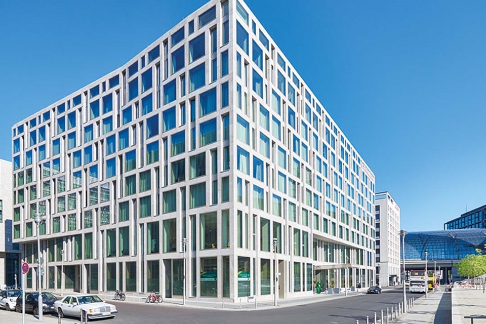 Modernes Bürogebäude mit geometrischer Fassade und reflektierenden Glasfenstern an einem sonnigen Tag