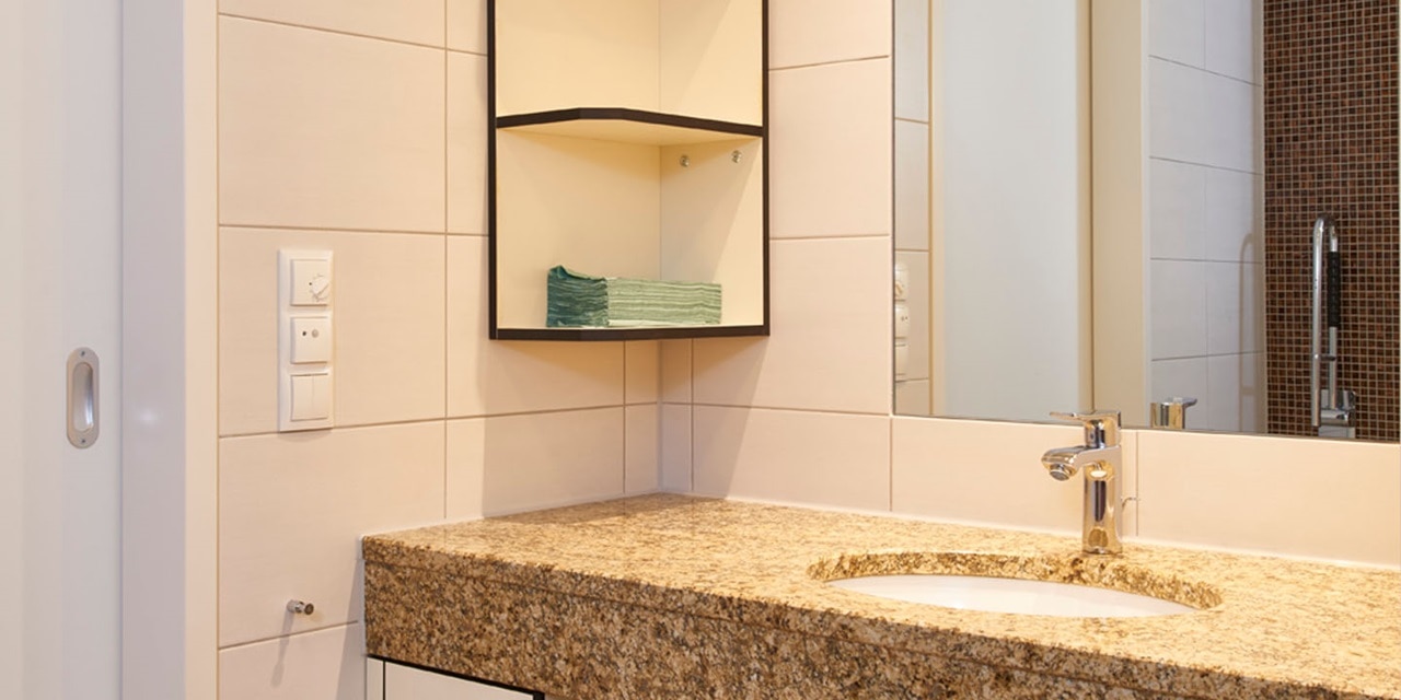 Modernes Badezimmer mit Granit-Arbeitsplatte, Waschbecken, Wasserhahn und wandmontierter Lichtschalter und Steckdose