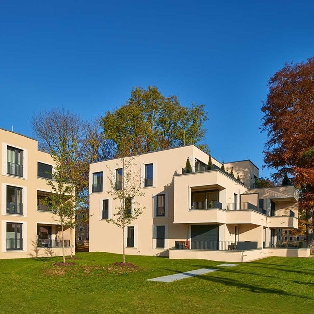 Moderne Wohngebäude mit Balkonen und grünem Rasen unter klarem blauem Himmel