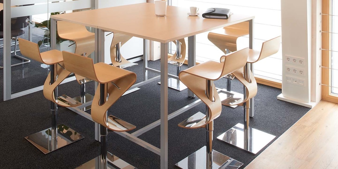 Modernes Bürointerieur mit hohem Besprechungstisch, Designerstühlen und Steckdosen auf der Säule