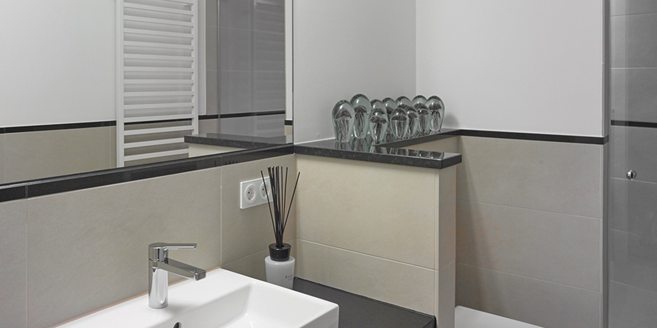 Modernes Badezimmer-Interieur mit elegantem Wasserhahn und weißem Waschbecken, Glasablage mit Trinkgläsern und Steckdose