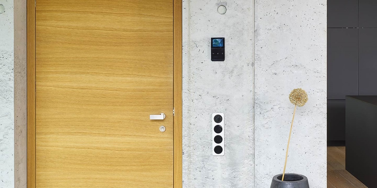 Modernes Interieur mit Holztür, wandmontiertem Touchscreen für Hausautomation und Türsprechanlage