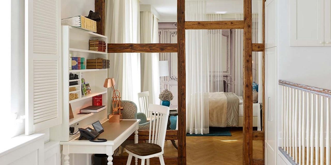Elegantes Innendesign eines Schlafzimmers mit Holzbalken, Schreibtisch und weißen Vorhängen