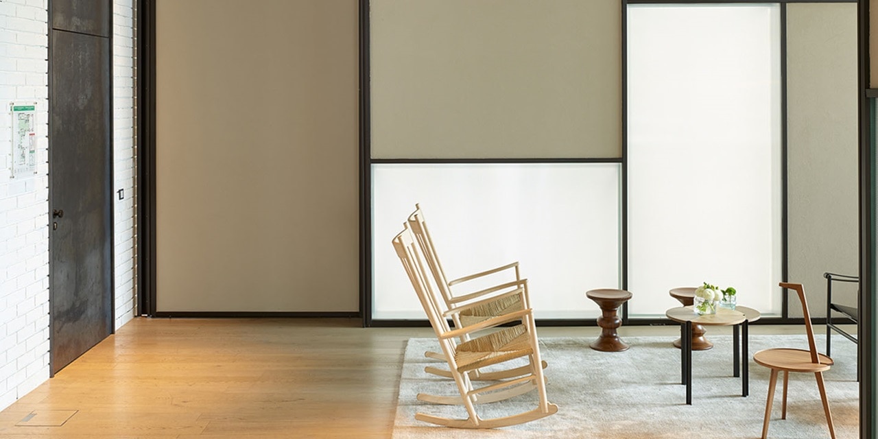 Modernes minimalistisches Wohnzimmer-Interieur mit Schaukelstuhl, Couchtischen und Schiebetürpaneelen