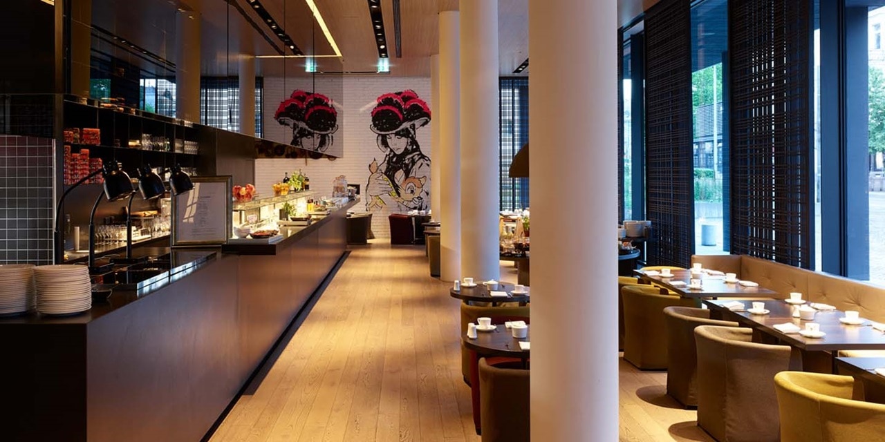 Modernes Café-Innenraum mit Buffettheke, stilvollen Hängeleuchten, Wandgemälde und Sitzbereich