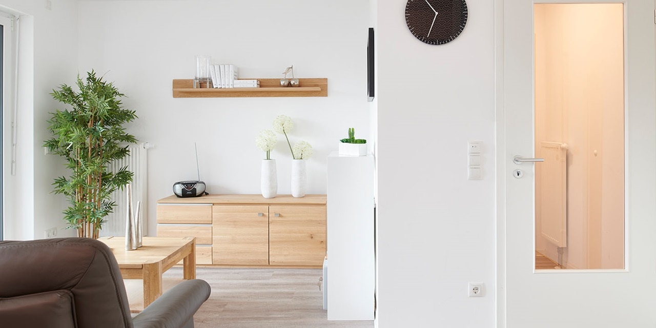 Modernes Wohnzimmerinterieur mit Holzmöbeln, Pflanzen und einem elektrischen Lichtschalter an der Wand