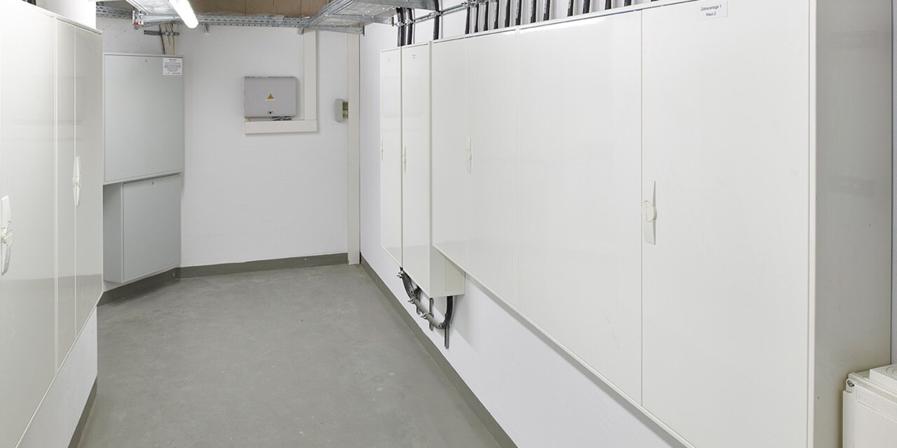 Moderner Elektroverteilungsraum mit weißen Schränken und sichtbarer Kabelkanalinstallation an den Wänden