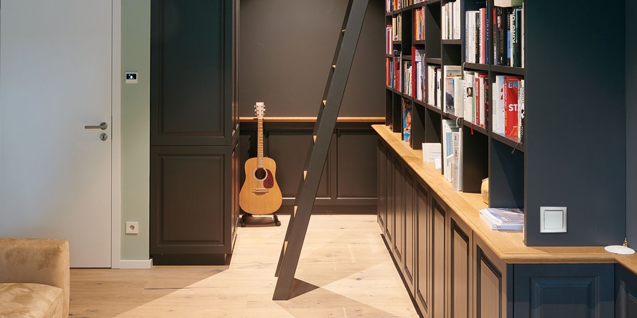 Modernes Wohndesign mit Holzbücherregal, Gitarre und Hager Lichtschalter an der Wand