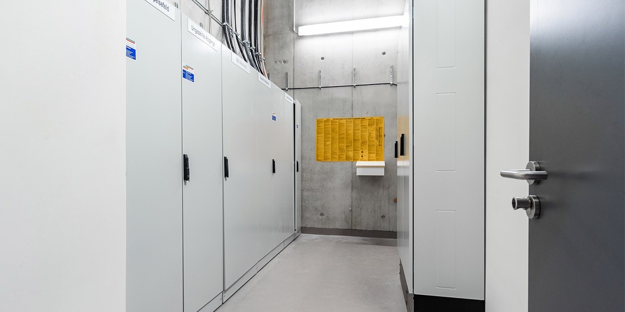 Moderner Elektro-Schaltanlagenraum mit mehreren geschlossenen Schränken und Betonwänden
