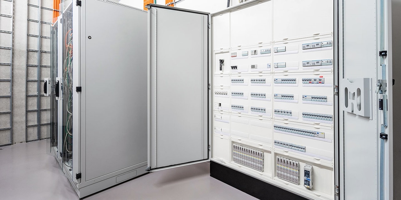 Elektroverteilungsschränke mit geöffneten Türen, die Leistungsschalter und Verkabelung in einer industriellen Einrichtung zeigen