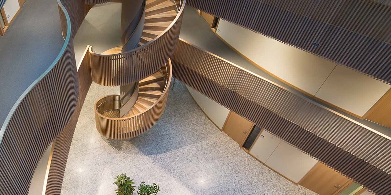 Innenansicht eines modernen Gebäudes mit spiralförmiger Holztreppe und Lamellenwänden