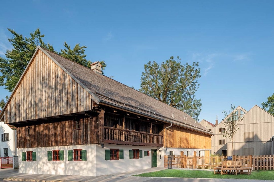 Traditionelles Holzhaus mit modernem Anbau vor klarem Himmel
