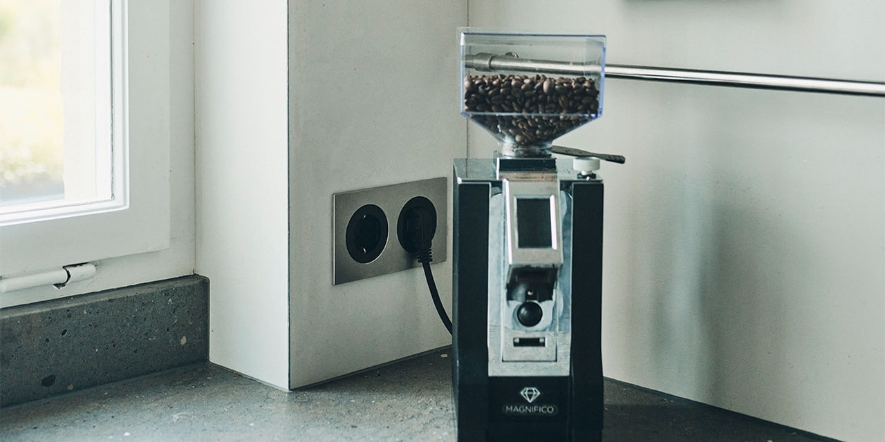 Kaffeemühle auf einer Küchenarbeitsplatte neben einer Doppelsteckdose