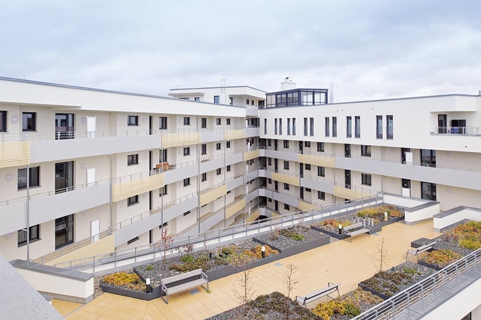 Modernes Wohngebäude mit Balkonen und zugänglicher Gartenterrasse