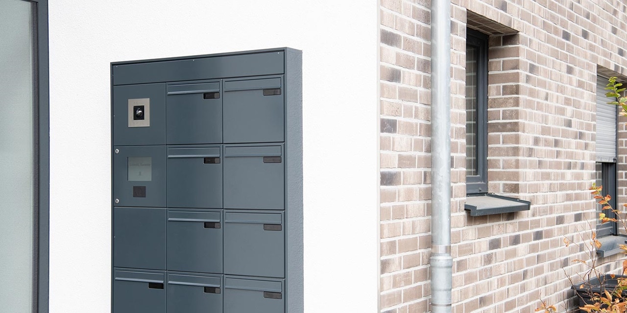 Modernes Briefkastensystem für Mehrfamilienhäuser an einer Außenwand neben einem Wohngebäude montiert