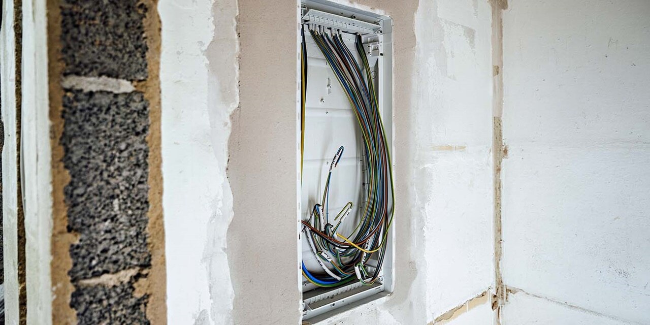 Offener Elektroverteiler mit ordentlich verlegten Kabeln in einer Wandnische installiert
