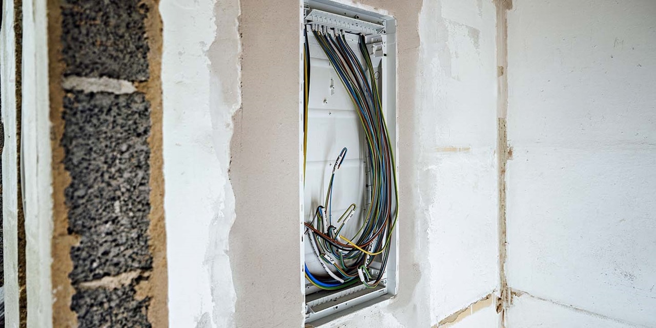 Offener Elektroverteiler mit ordentlich verlegten Kabeln in einer Wandnische installiert