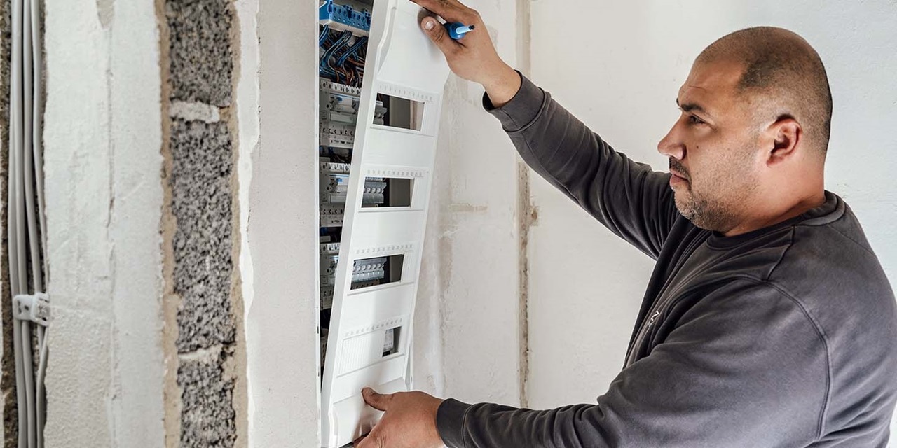 Elektriker montiert einen Hager Verteilerkasten mit Leitungsschutzschaltern in einem Wohngebäude
