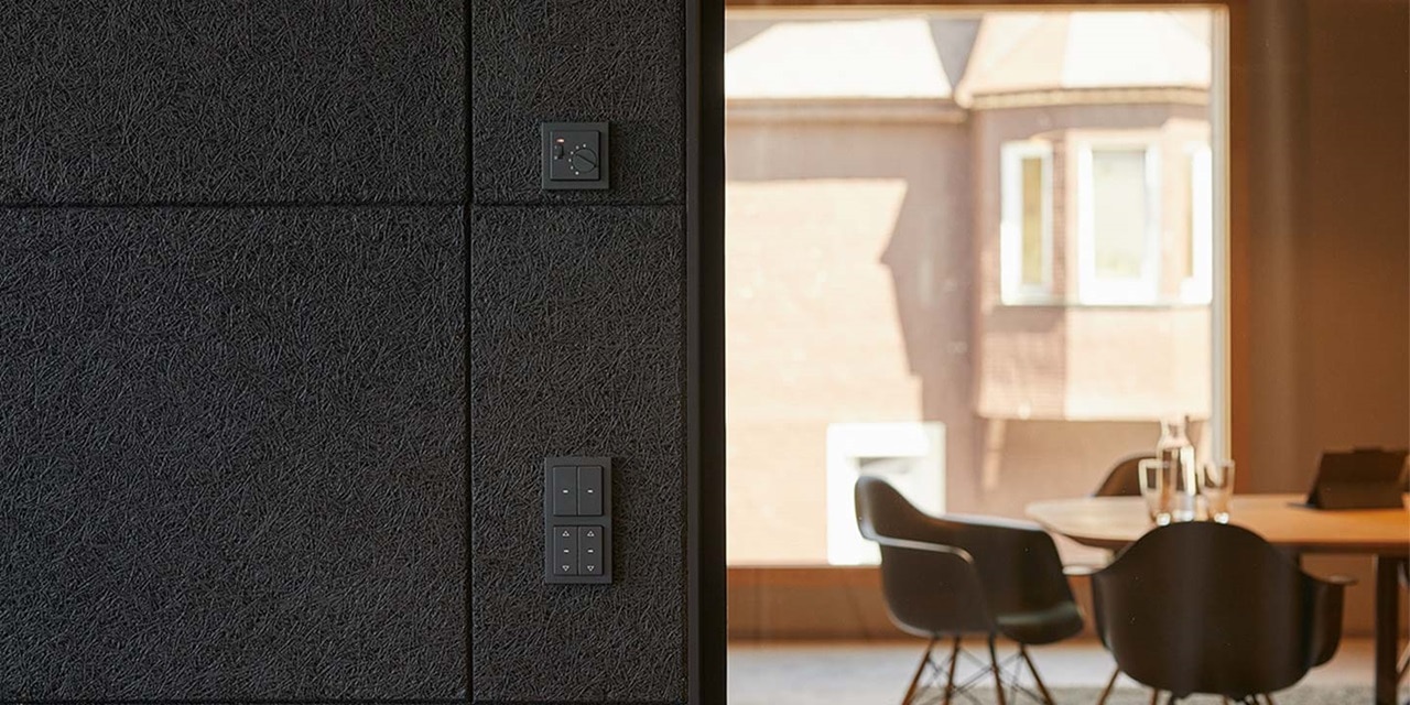 Modernes Bürointerieur mit an der Wand montierten Lichtschaltern und Thermostat von Hager an strukturierter Wand