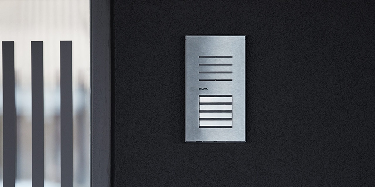 Modernes Sprechanlagensystem an einer dunkel texturierten Wand in der Nähe einer Glasscheibe installiert